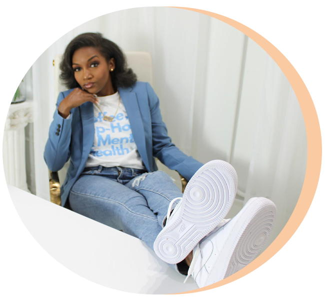 Brittany Rogers seated in a blue blazer with white sneakers propped on a desk